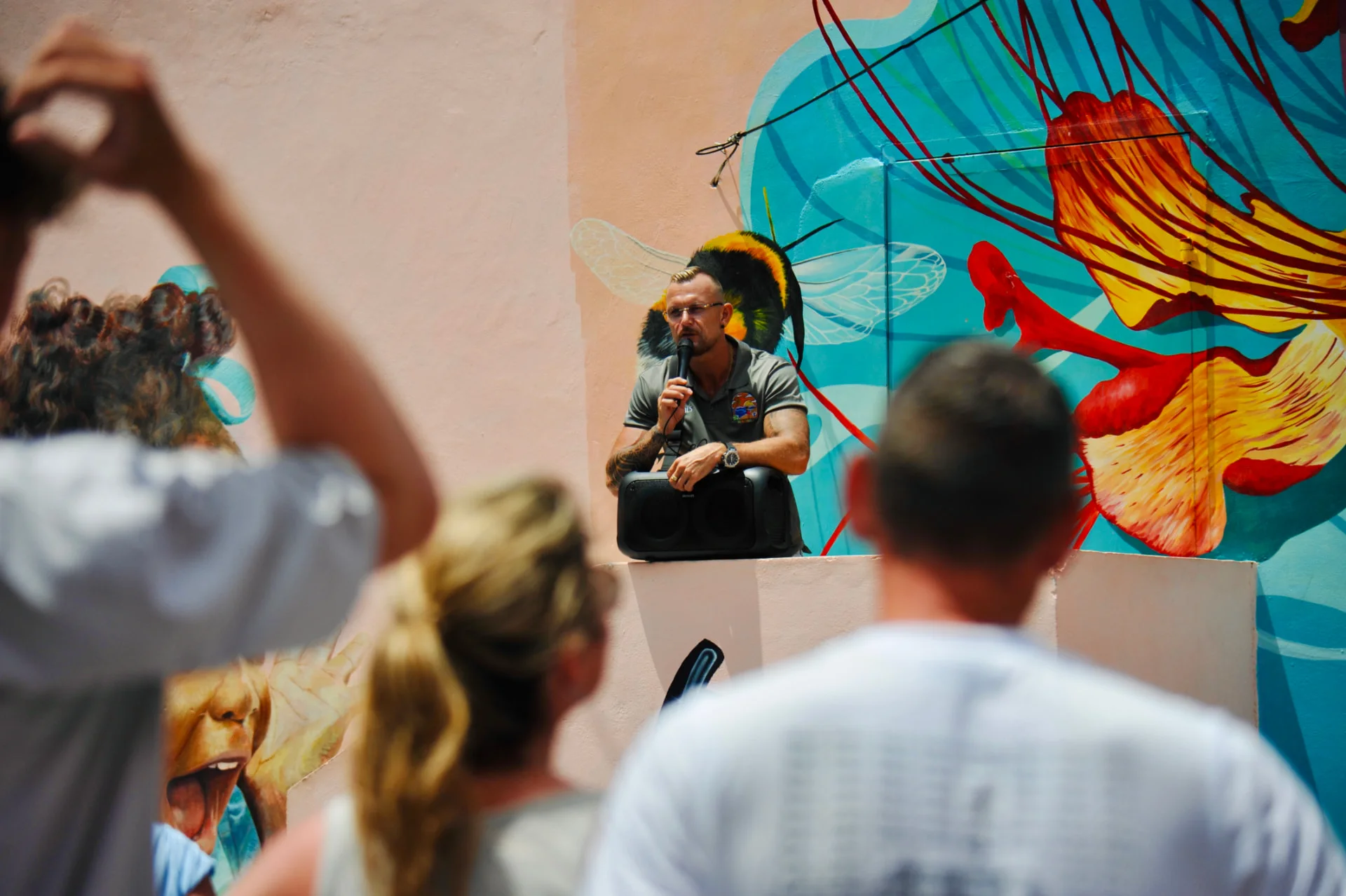 Nils mit Mikrofon während der CuraVida Inseltour vor Gästen und bunter Streetart