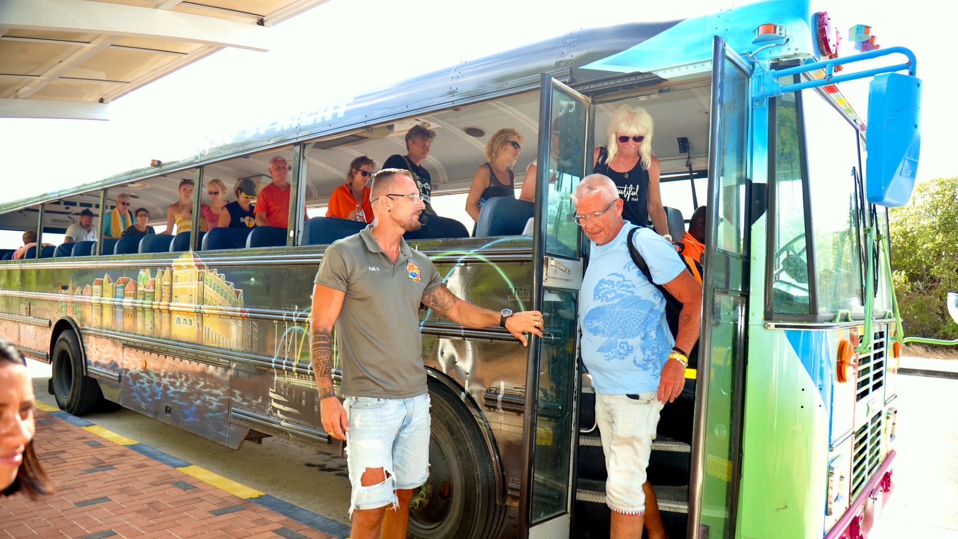 Guide von Next Level Travel öffnet die Tür des farbenfrohen CuraVida-Schulbusses