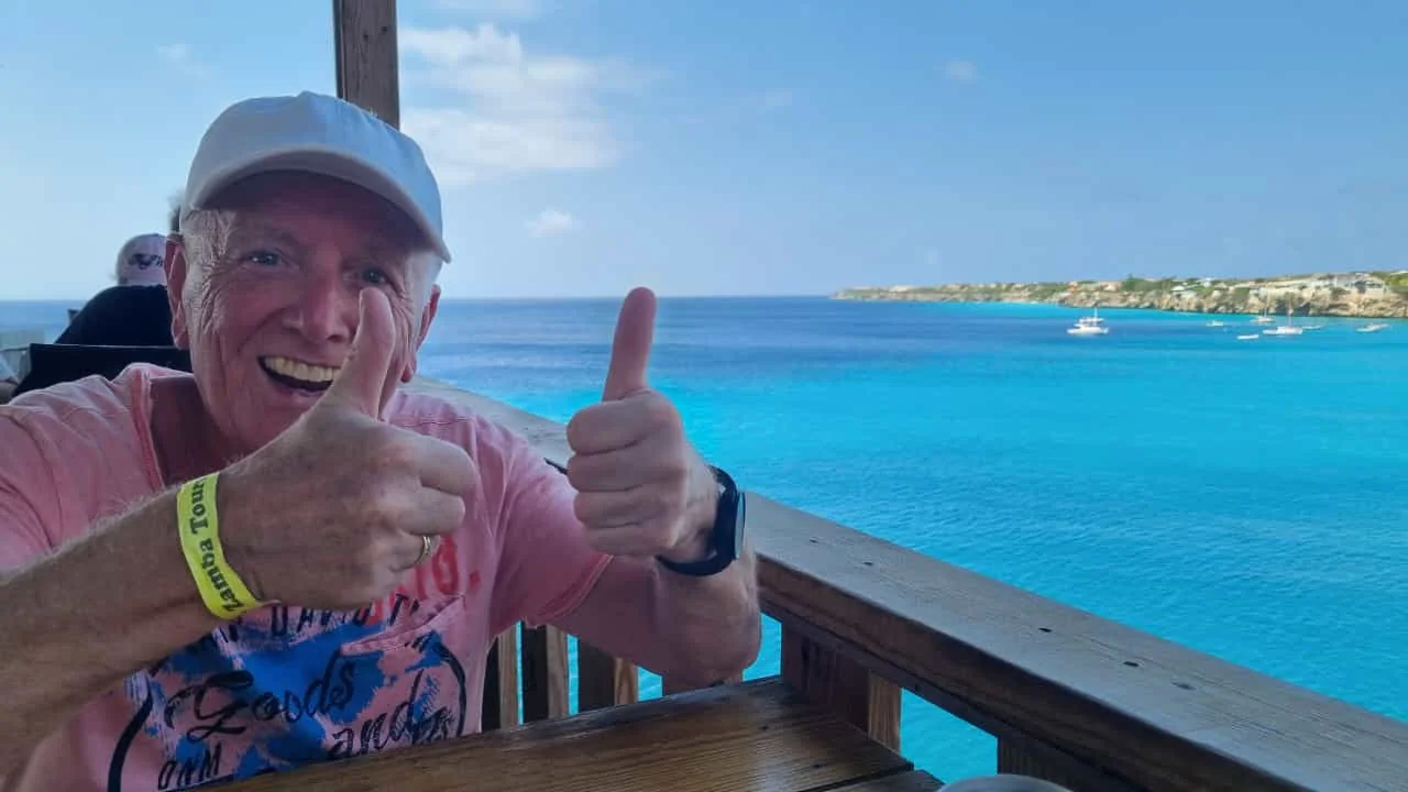 Gast mit Daumen hoch auf einer Terrasse über dem türkisfarbenen Meer